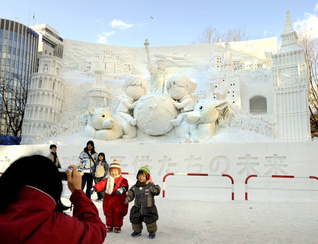 Children pose in front of the snow sculpture at the Odori park in central Sapporo on February 5, 2008. The annual Sapporo Snow Festival kicked off today with the hundreds of beautiful snow statues and ice sculptures. AFP PHOTO / KAZUHIRO NOGI / AFP / KAZUHIRO NOGI